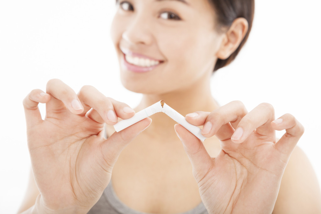 smiling woman breaking cigarette and no smoking concept